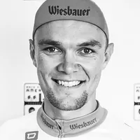 A man wearing a cycling outfit with the 'Wiesbauer' logo on the cap and shirt.