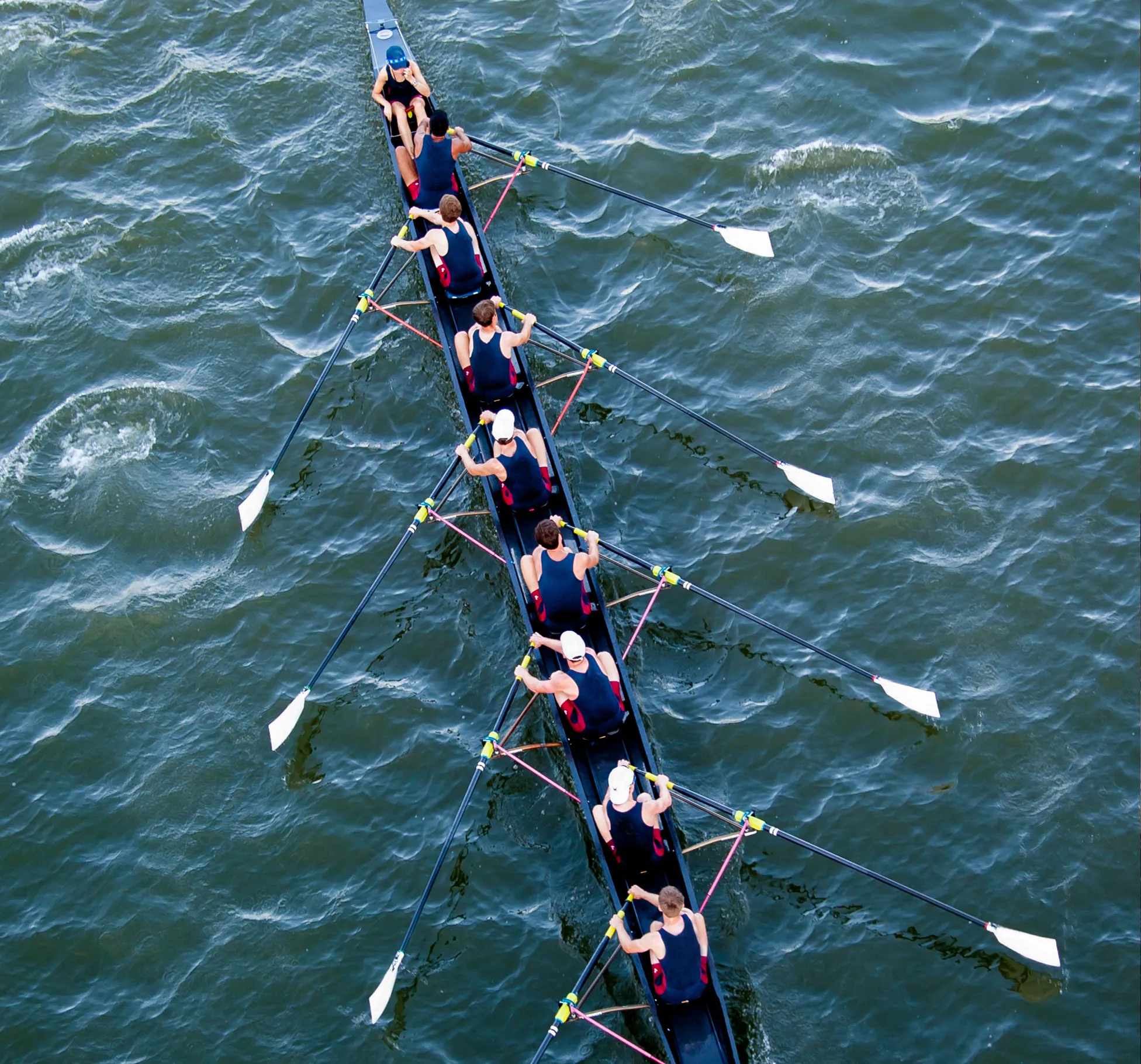 A group of rowers in matching sportswear rowing in sync on a body of water.